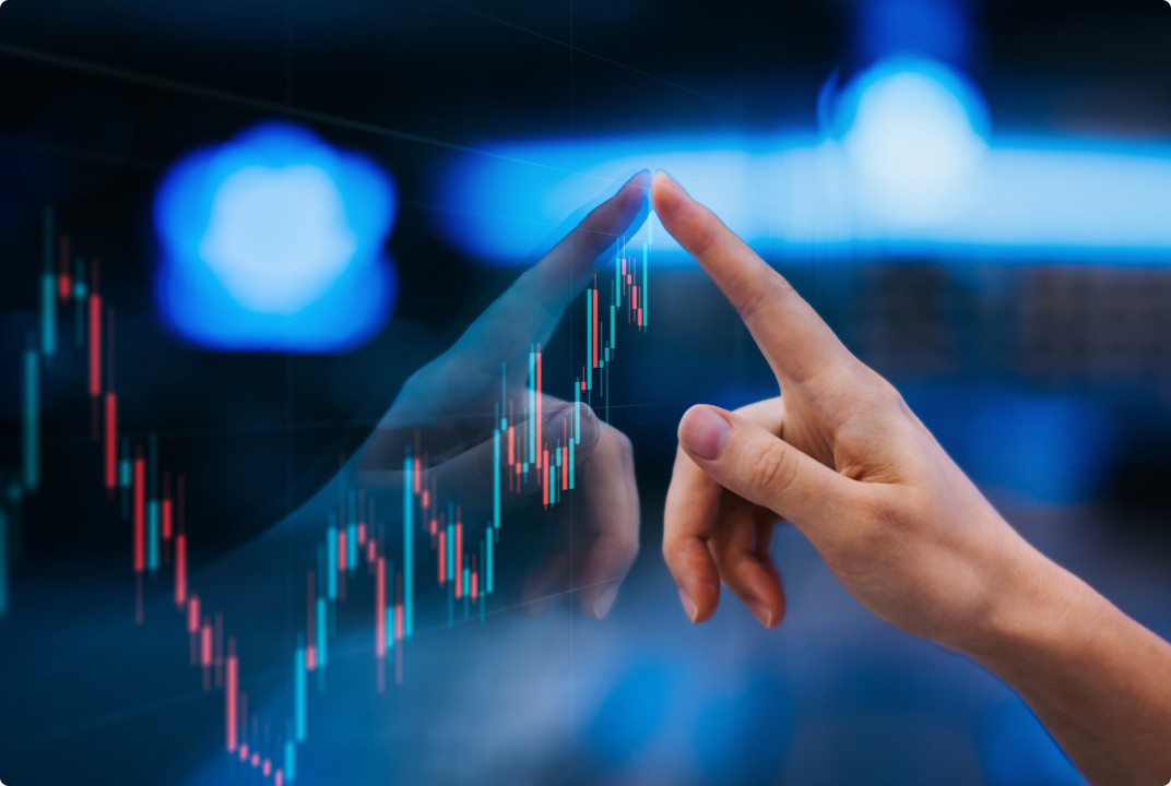 Mão de uma pessoa tocando uma tela digital com gráfico de candlestick, representando a análise de ações ou dados financeiros em um ambiente tecnológico, com luzes azuis de fundo.